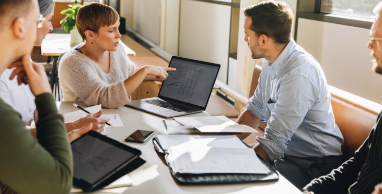 A group of people looking at a laptop and discussing.
