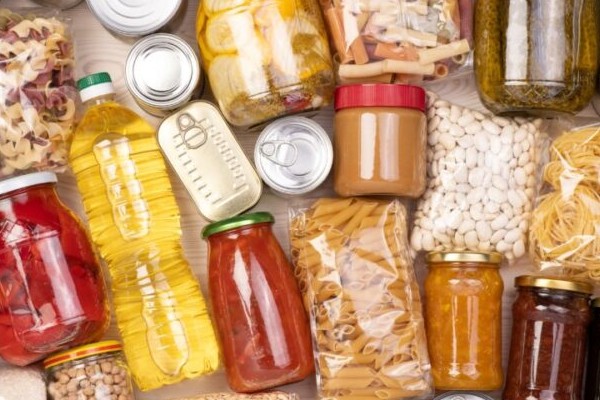 A table covered in various cans and bottles and jars of food.