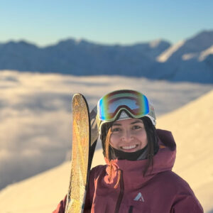 Brenda holding her skis on a mountain.