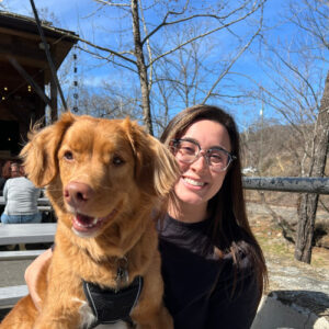 Emily smiling at the camera with her dog.
